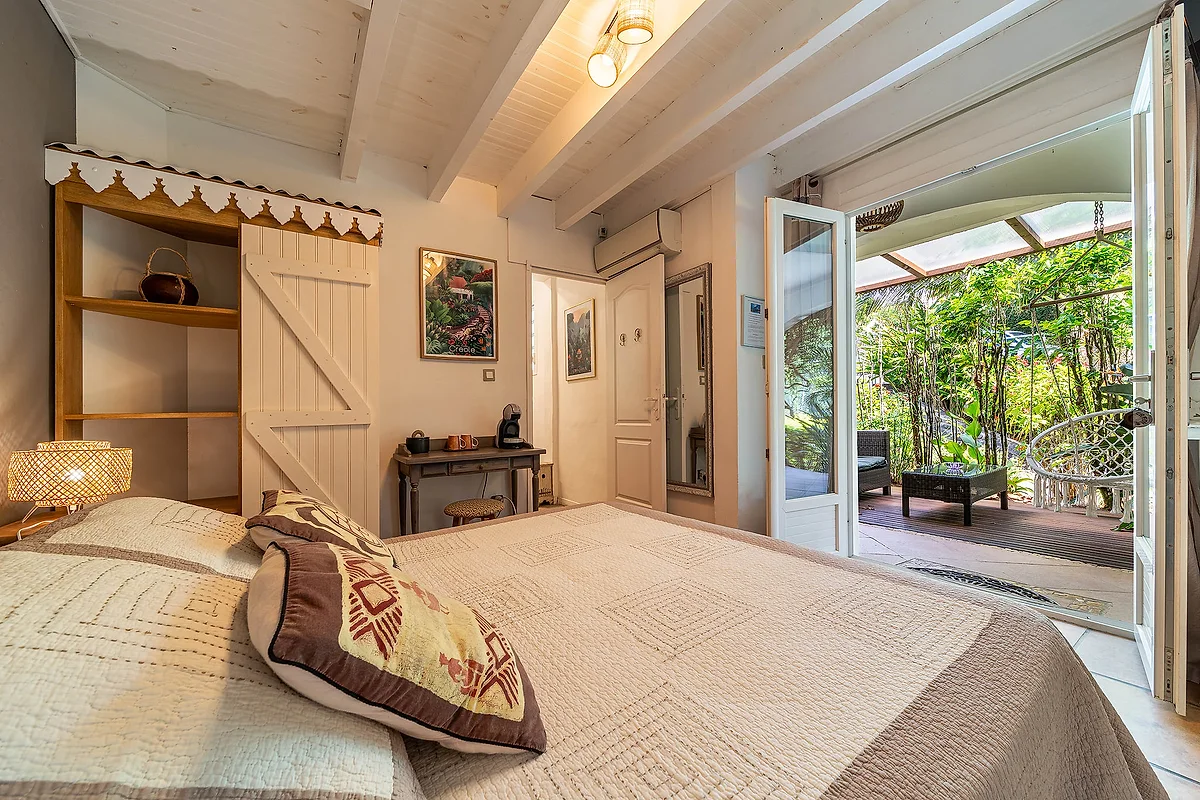 La chambre Créole, son lit et sa porte ouverte sur la terrasse