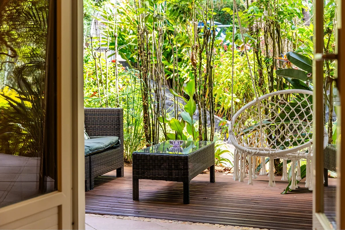 La terrasse de la chambre Créole et son fauteuil suspendu dans le jardin
