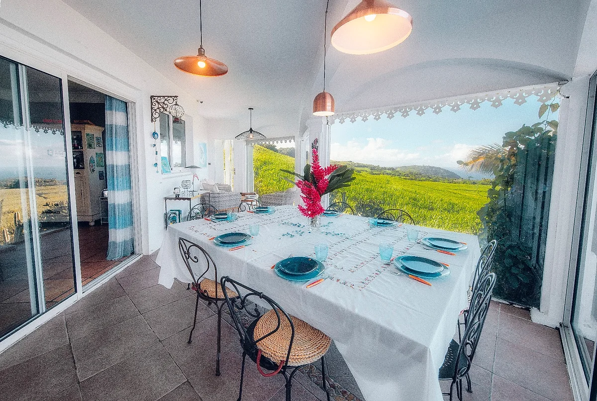 La table d'hôtes dressée sous la varangue, avec la vue sur les cannes et la mer