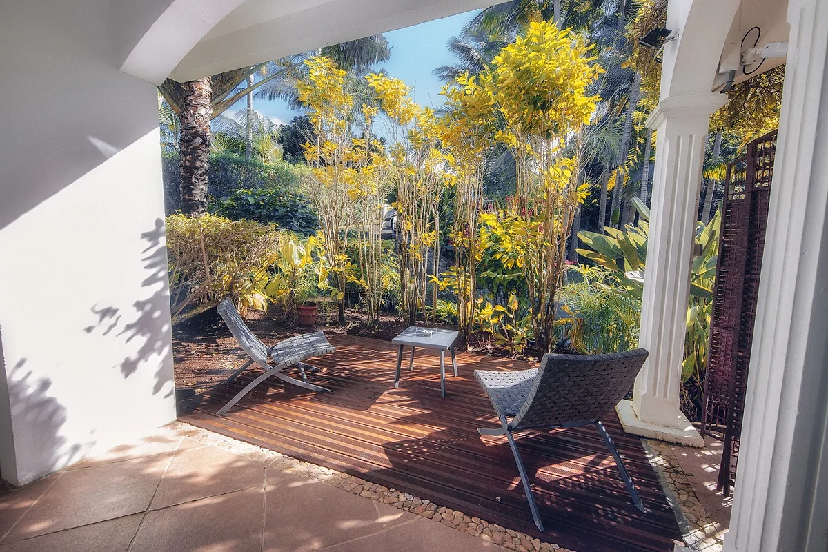 Une terrasse en bois dans le jardin, sous les palmiers et les bambous
