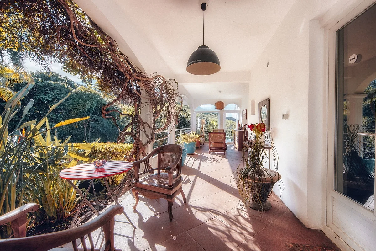 La varangue de La Plantation, ses tables et ses plantes, ouverte sur le jardin